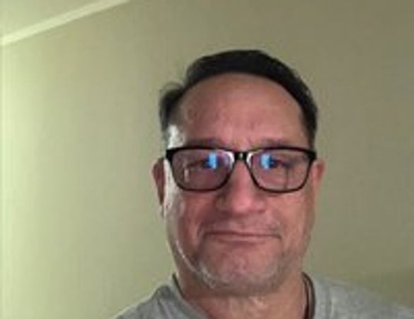 Middle-aged man with glasses smiling indoors.