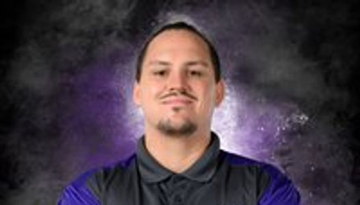 Man with a confident smile against a dark purple and black background.