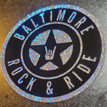 Holographic sticker with Baltimore Rock &amp; Ride logo and rock hand sign.