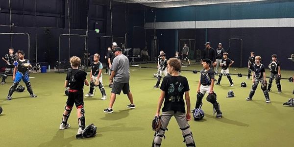 Young baseball players warming up indoors.