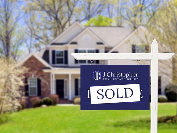 Sold sign in front of a house by J. Christopher Real Estate Group.