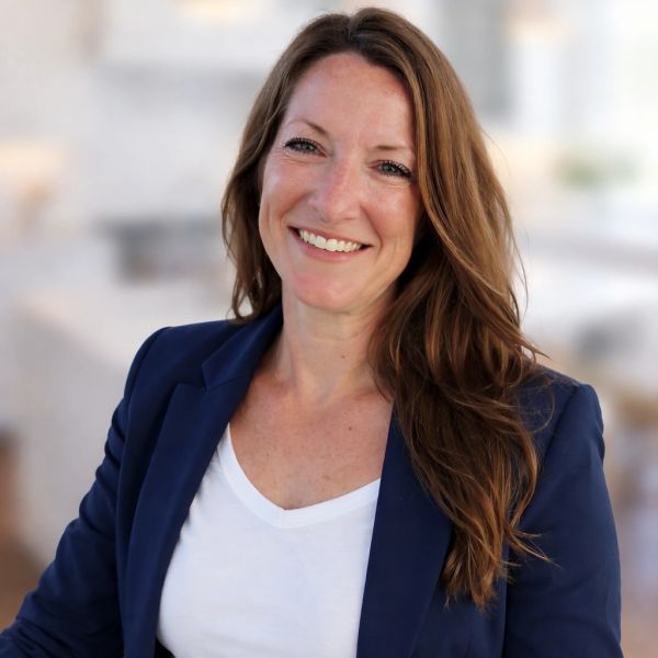 Smiling woman with long brown hair in a navy blazer and white shirt.