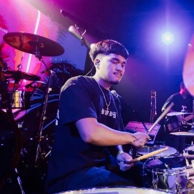 Drummer playing on stage with colorful lights.