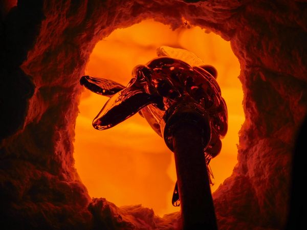 Molten glass being shaped inside a glowing furnace.