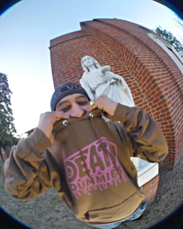 Person posing in front of a statue and brick building.