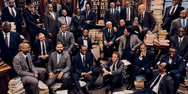 A large group of men in suits gathered in a library, surrounded by stacks of books.