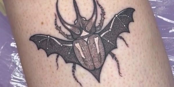 Tattoo of a beetle with bat wings and constellation dots.