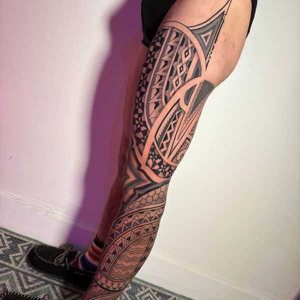 Intricate Polynesian-style leg tattoo on a person.