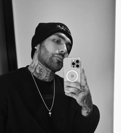 Man with tattoos takes a black and white mirror selfie.