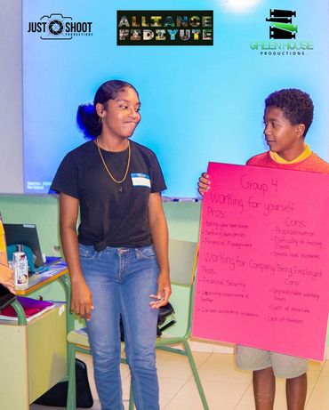 Two students presenting pros and cons on a poster in a classroom.