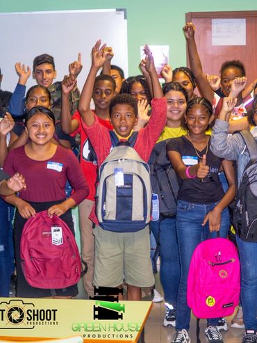A diverse group of students enthusiastically posing with backpacks in a classroom.
