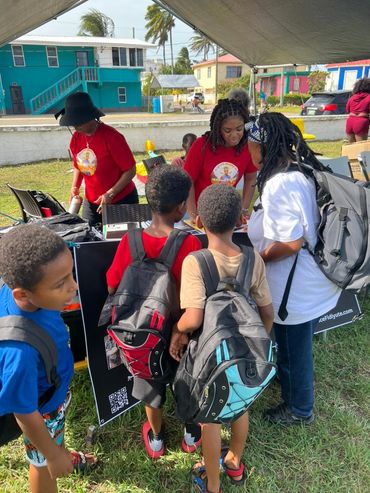 Children and adults interact at an outdoor event booth under a tent.