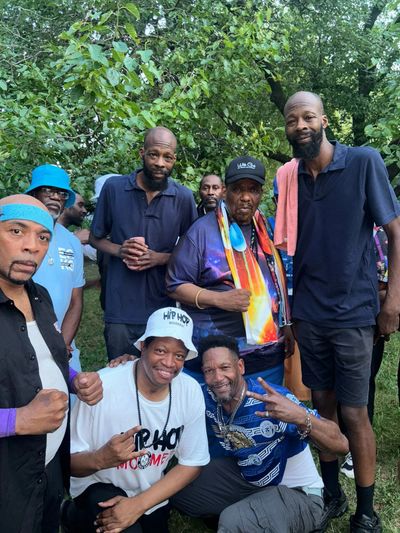 Group of men posing outdoors with smiles and peace signs.