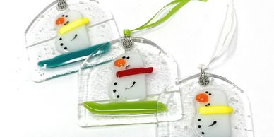 Three ornaments named "Toboggan Tom"  which features a snowman wearing a scarf while sitting on a to