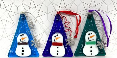 Group of 3 snowmen on a three shaped background decorated with a snowflake charm.