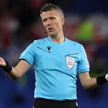 Football referee in blue uniform signaling during a match.