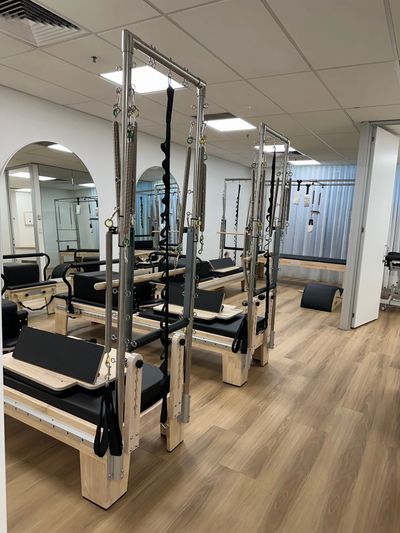 A clean Pilates studio with reformer machines and wooden floors.