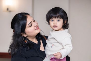 A woman lovingly holds a toddler in a cozy indoor setting.