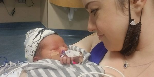 A mother lovingly gazes at her newborn baby wrapped in a hospital blanket.