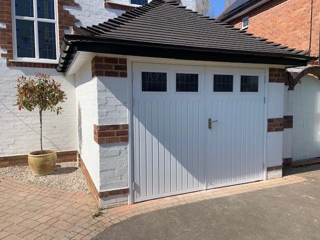 White garage door with small windows on a brick house.