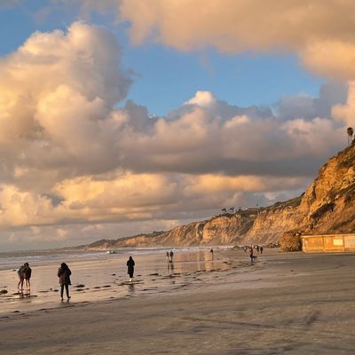 People walking on Blacks Beach at Sunset. Clouds.