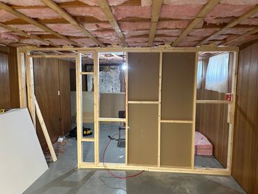 Basement room under construction with exposed insulation and wooden framing.