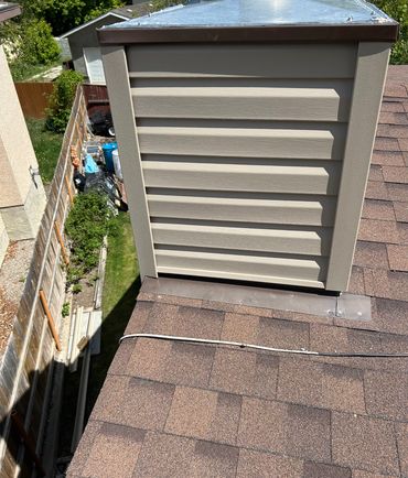 View of a rooftop with a chimney and backyard storage.