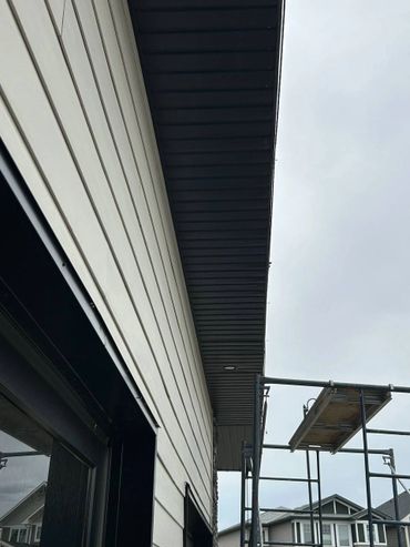 Construction scaffolding near a house's exterior wall and roof.