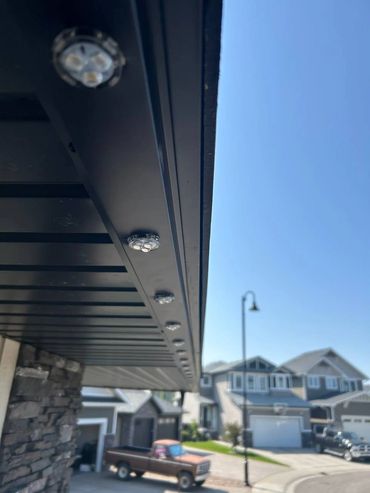 Close-up of LED lights under a porch roof in a suburban neighborhood.
