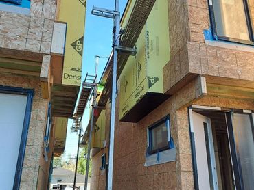 Partially constructed wooden houses with scaffolding and blue sky.