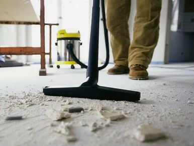 Person vacuuming construction debris from the floor.