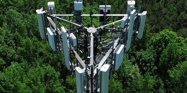 Top view of a cell tower surrounded by dense green forest.