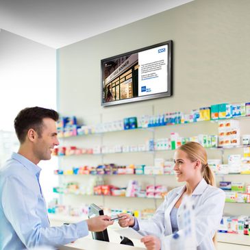 Pharmacist assisting a smiling man at the pharmacy counter with medicines.
