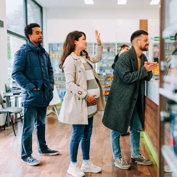 People waiting in line at a pharmacy counter.