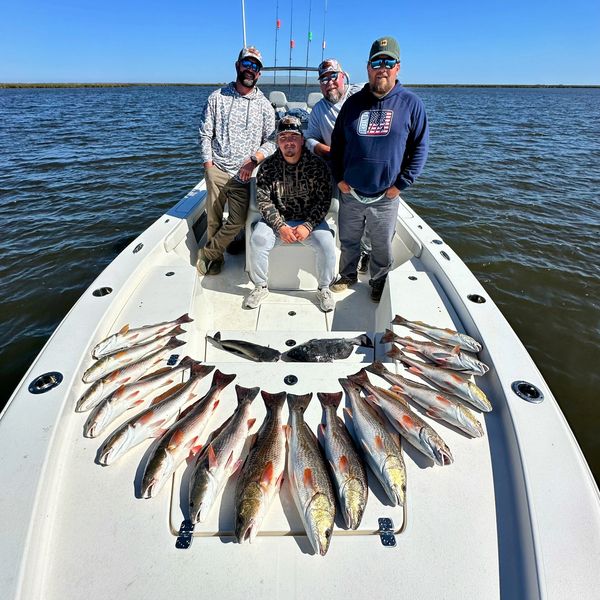 4 person guided fishing trip with guys standing on a boat in front of a limit of redfish in NOLA.