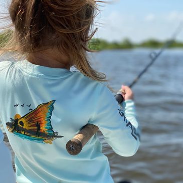 Back of child fishing holding a fishing rod with marsh of Delacroix, LA in the background