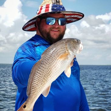Smiling male fisherman holding a Red Drum fish