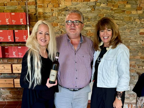 Three people posing with a wine bottle indoors.