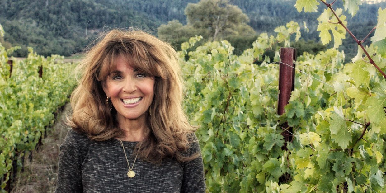 Smiling woman standing in a vineyard.