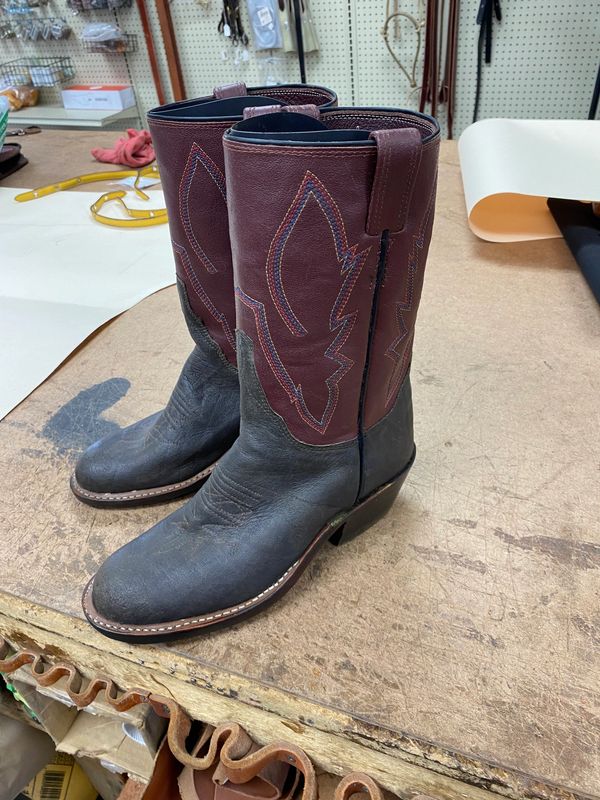 Two-tone leather cowboy boots on a workbench.