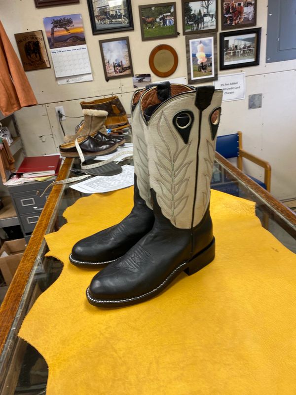 Black and white cowboy boots on a yellow leather hide.
