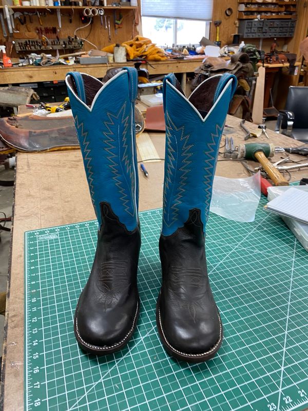 Pair of black and blue cowboy boots on a cutting mat.
