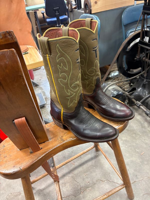 Pair of vintage cowboy boots on a wooden chair.