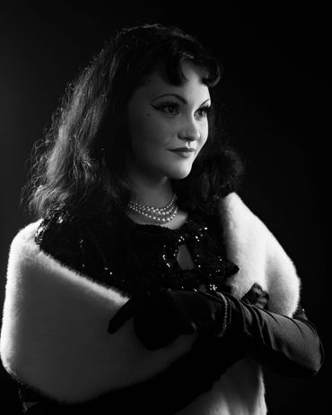 Vintage black and white portrait of a woman in elegant attire with pearl necklace.