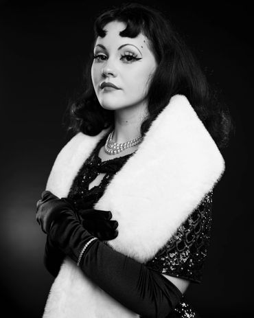 Elegant woman in vintage attire with fur stole and gloves.
