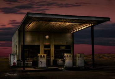 Abandoned gas station at dusk with a dramatic sky.