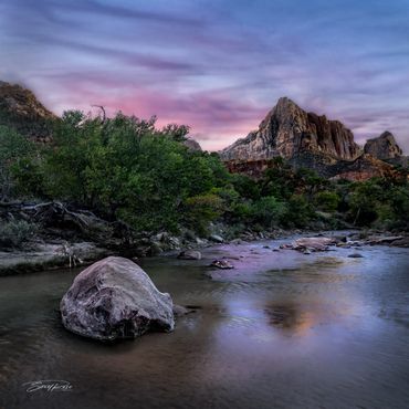 Serene river flowing through a rocky landscape at sunset.