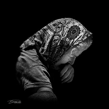 Black and white portrait of an elderly woman wearing a patterned headscarf.