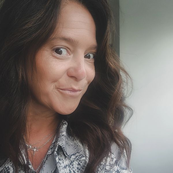 Close-up of a woman smiling with wavy hair.