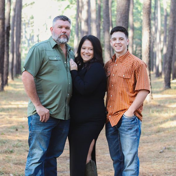 A family poses together in a pine forest.